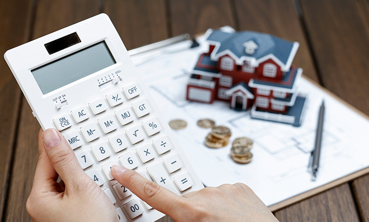 Persona calculando cuanto impuesto se paga al vender una casa en calculadora